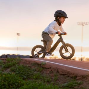 Child rides Giant Pre rCarbon strider bike at sunset on a pump track.