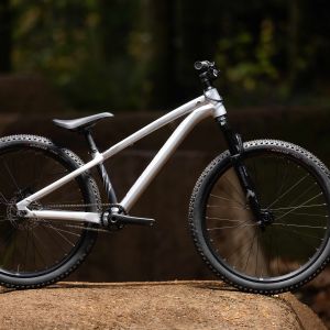 A Giant STP 26 staged in the forest on a dirt jump.