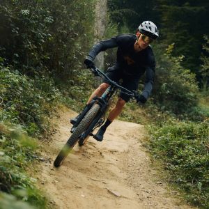 A mountain biker riding a Giant Talon E+ mountain bike drops into a bermed descent.