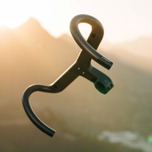 A close up view of the under side on the CADEX Aero Integrated Road Handlebar floating in front of a mountain back drop.