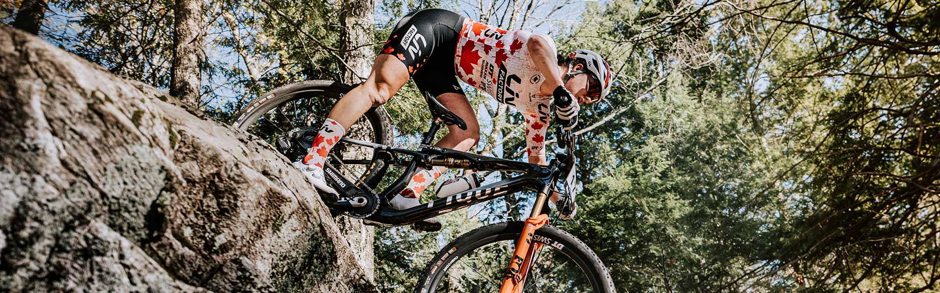 woman riding over boulder on xc bike