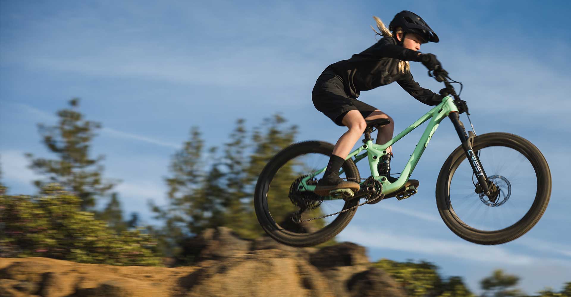 Girl riding Faith off a rock jump