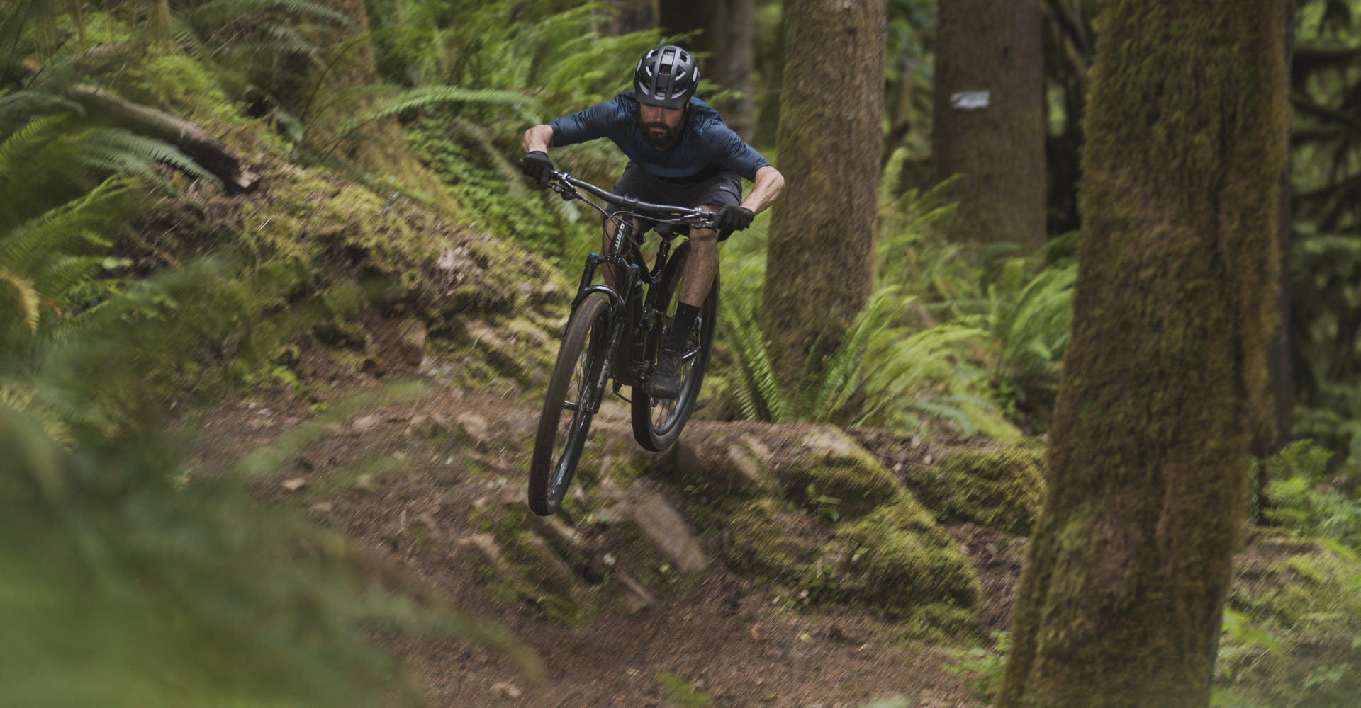 man riding 29 inch full suspension mountain bike down a bike trail