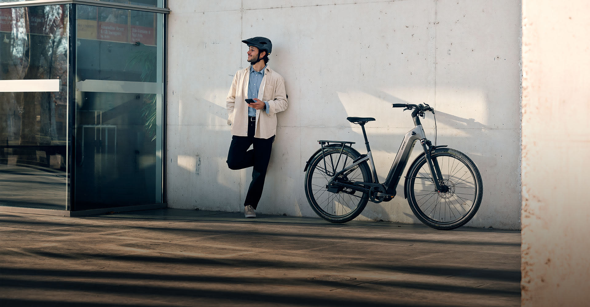 cyclist leaning against wall by electric bike