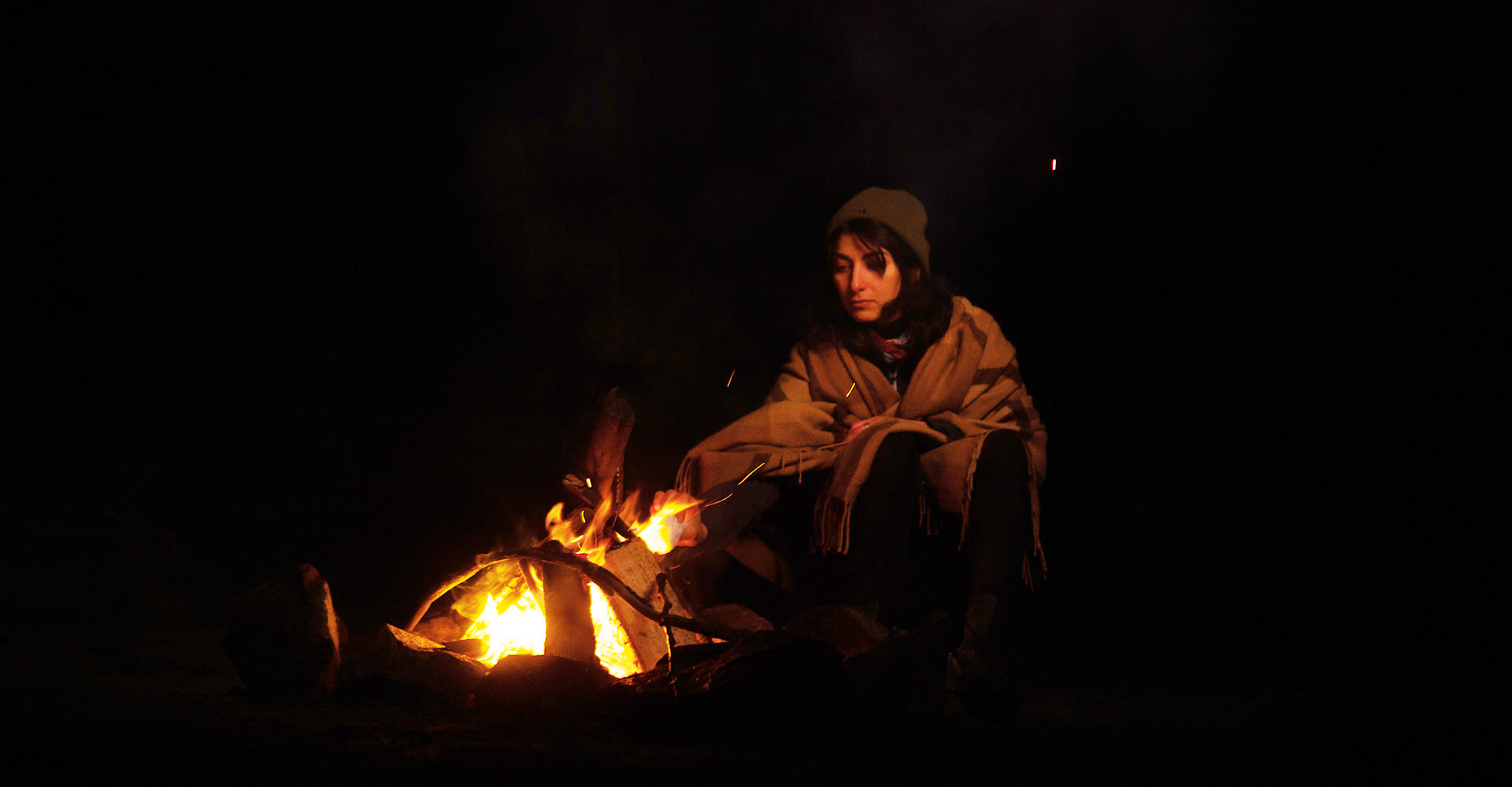 Mahshid sits by fire.