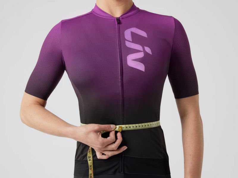 A woman measuring her waist in a cycling kit