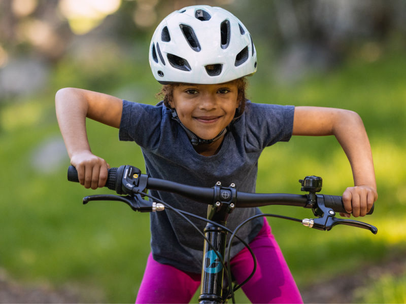 a young girl standing over a mountain bike