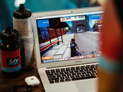 A stationary bike rider looking at her Zwift avatar on a laptop
