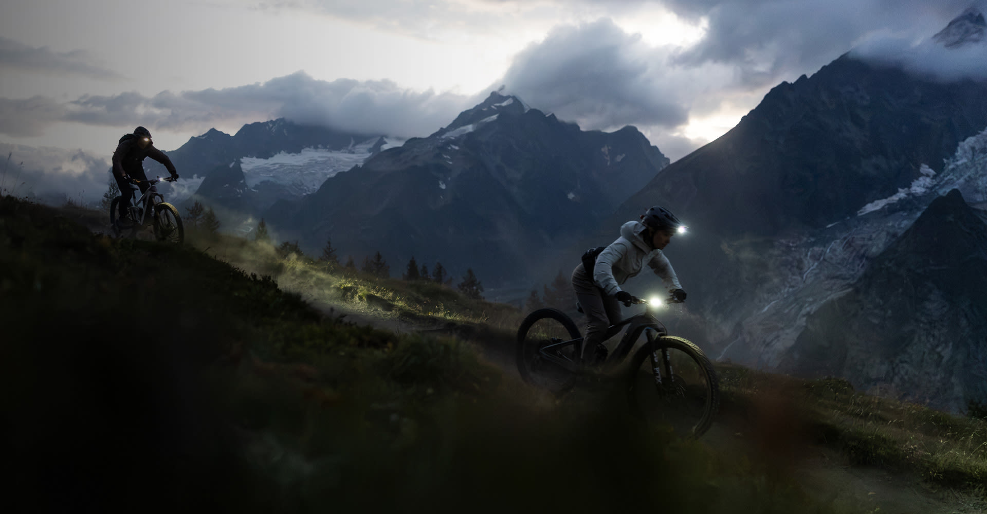 Two mountain bikers riding at night.
