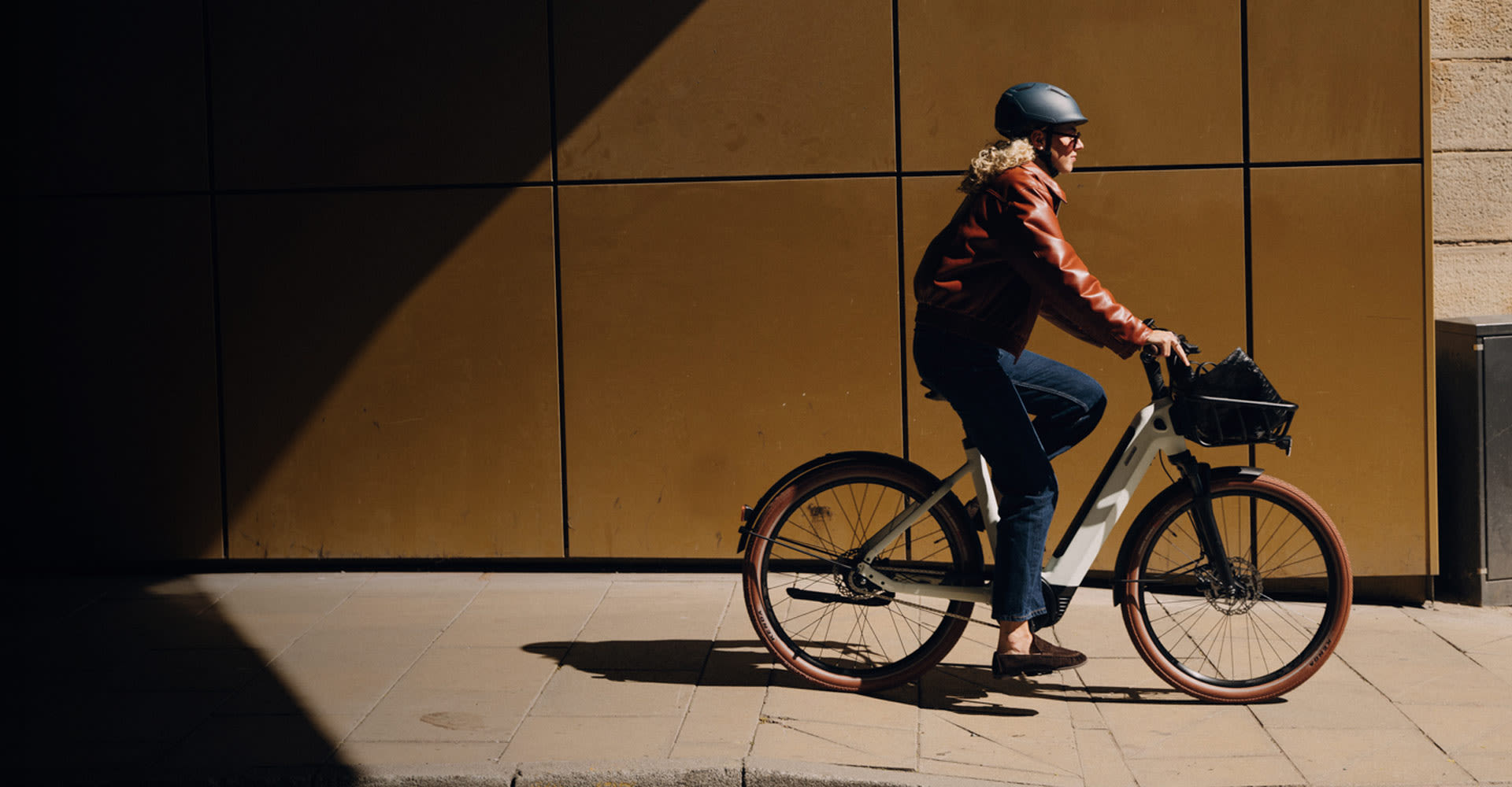 Woman riding Liv Flourish E+ bike on a sidewalk.