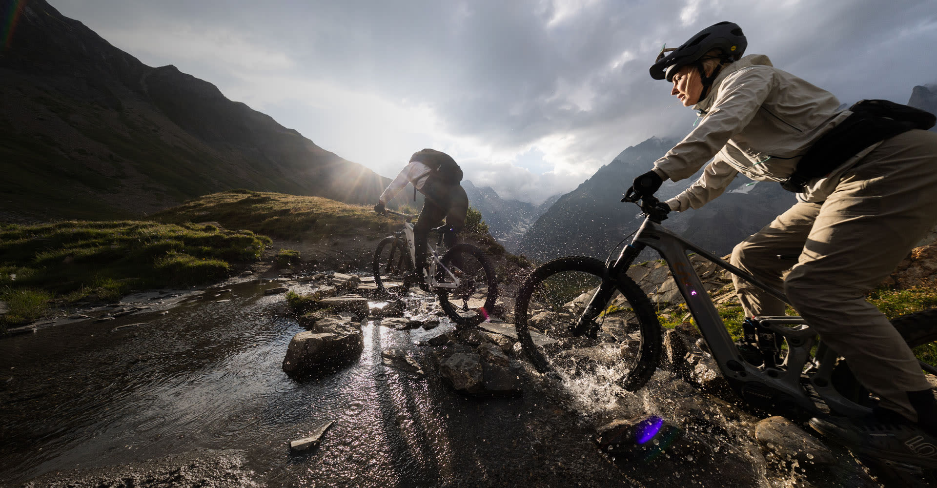 Mountain bikers riding through a puddle in the mountain. 