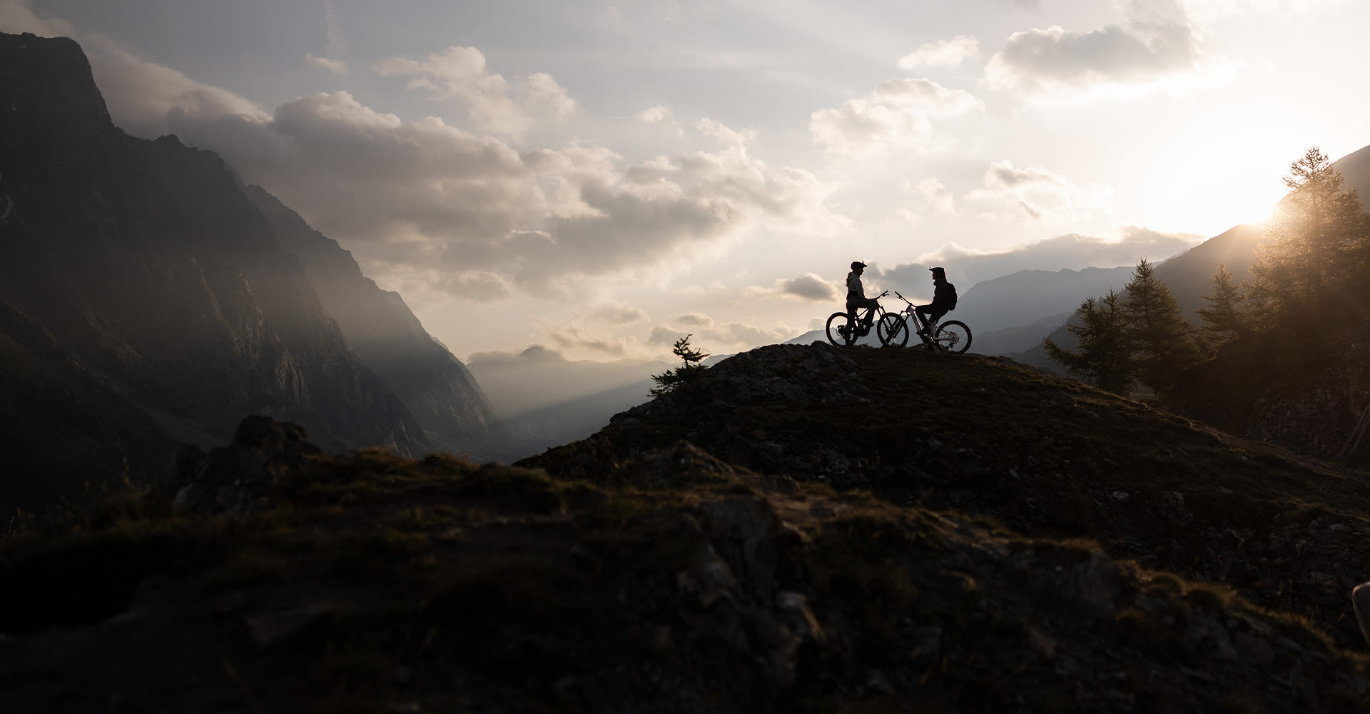 Silhouette of two riders on a mountain top.