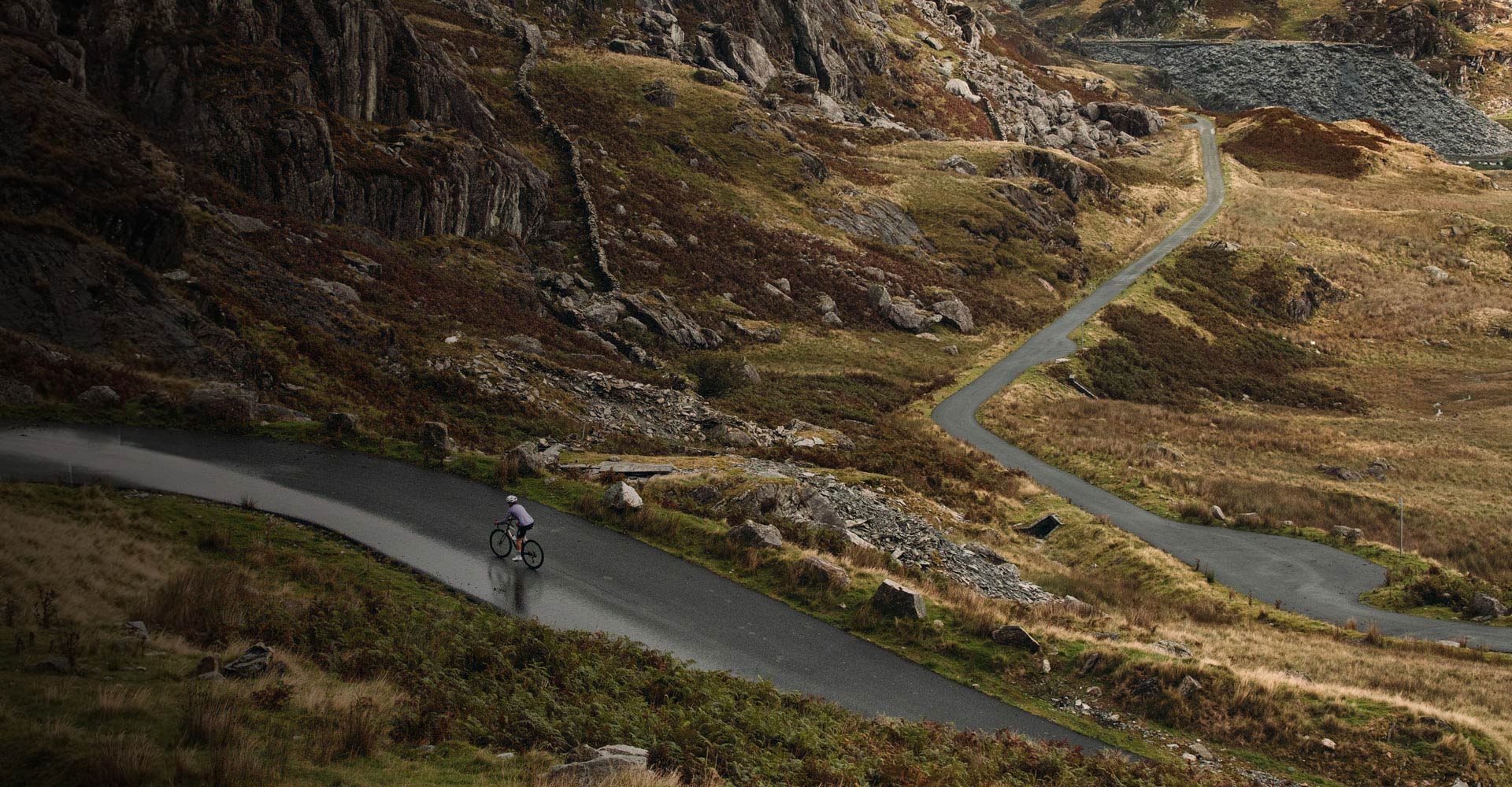 A woman riding an Avail up the road in the distance, tree cover.