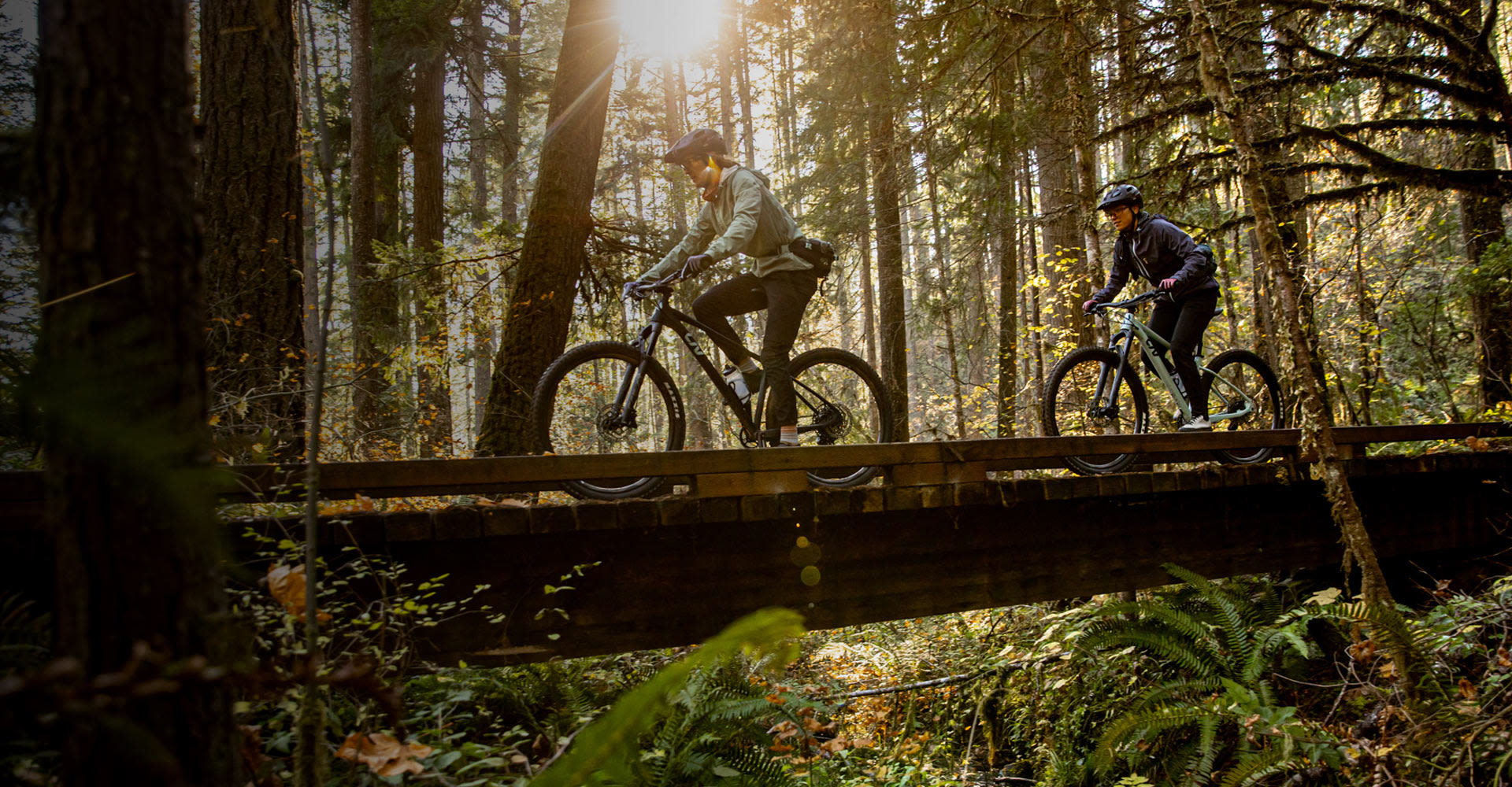 two women riding hardtail mountain bikes on a bridge