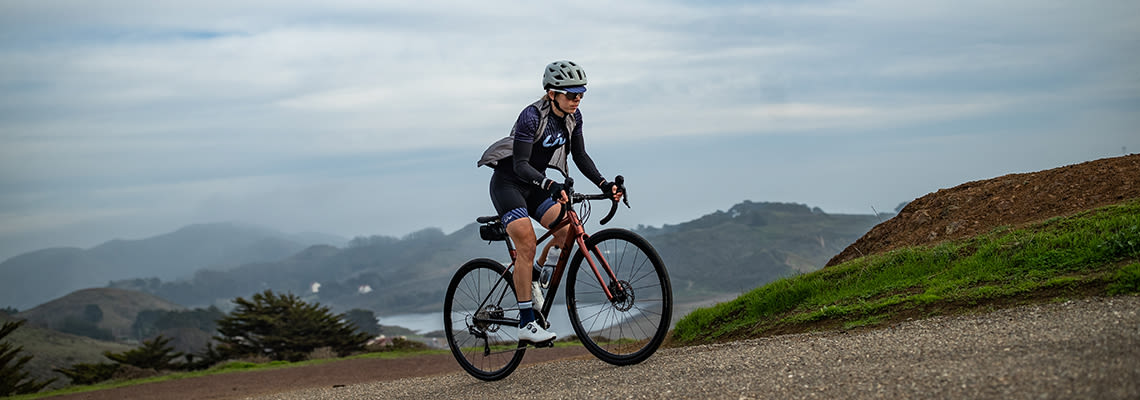 image of a woman riding her liv road bike on a path by the coast