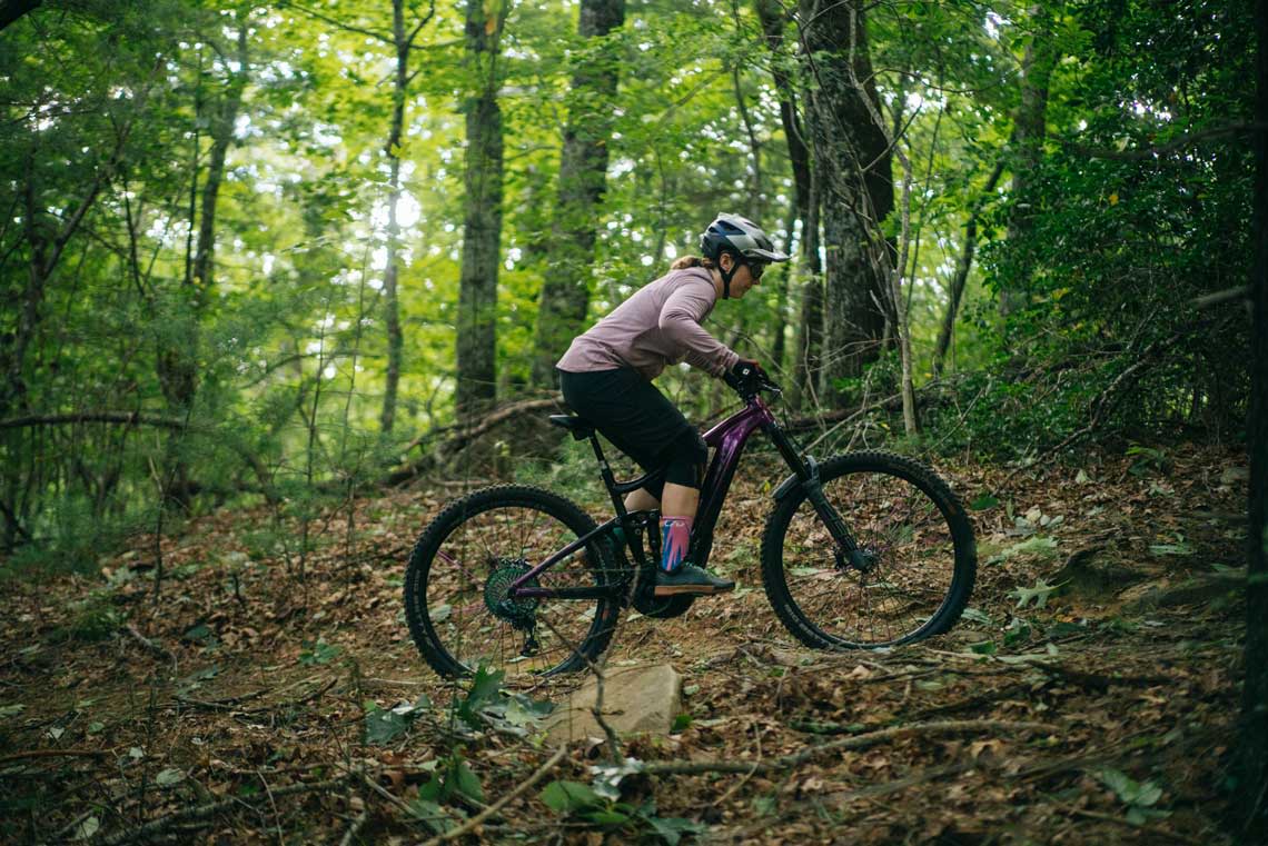a woman climbing on an e-mtb with her chest down